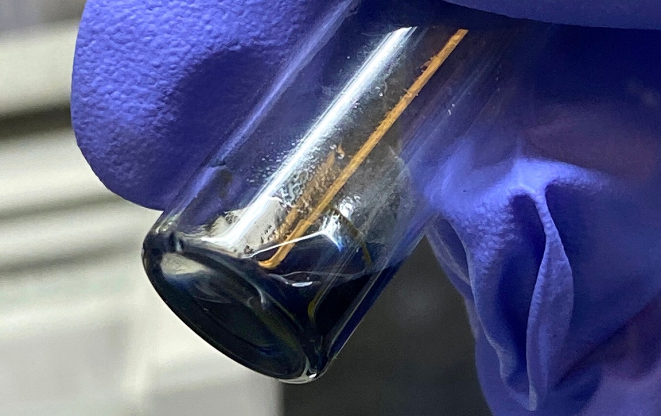 Zoom image: The purple/blue solution in this vial contains crystals of the berkelocene “sandwich.” Photo: Alyssa Gaiser/Berkeley Lab 