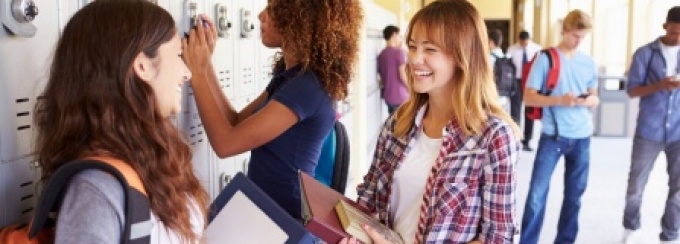 Students gather near school lockers in a hallway.
