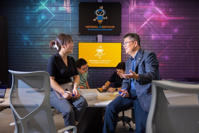 Jinjun XIong talking with a student at the National AI Institute for Exceptional Education office. 
