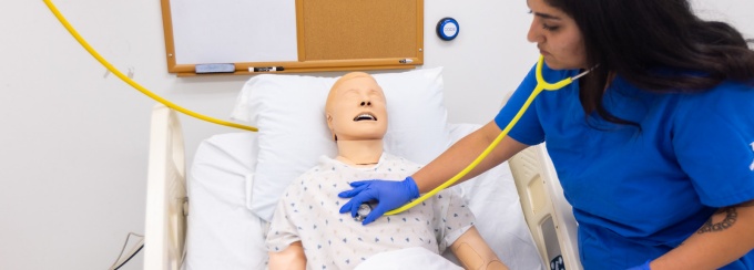 A student nurse examines a dummy patient in UB's nursing simulation lab. 