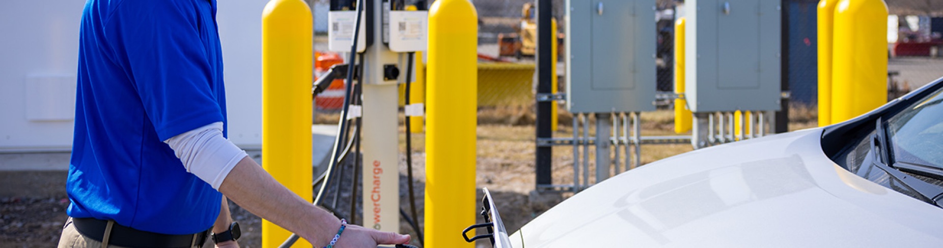 A University at Buffalo employee plugging a charger into an electric vehicle.
