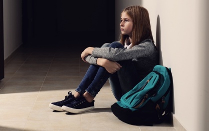 A student sitting alone in a hall with her bookbag. 