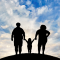 Concept of a bright future for a family struggling with obesity featuring silhouettes of three family members standing on a hill with a bright blue sky in the background.. 
