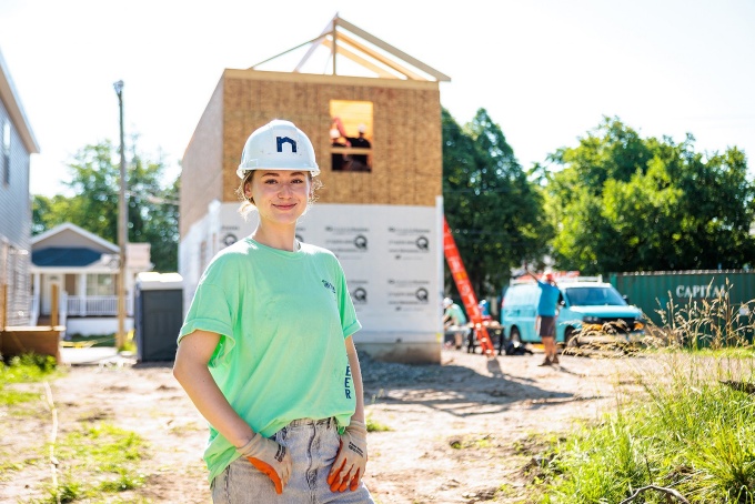 Social Impact fellow Emily Dickey poses near a habitat for humanity house under construction.