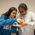 Two teenagers smile while working together on a STEM project. 