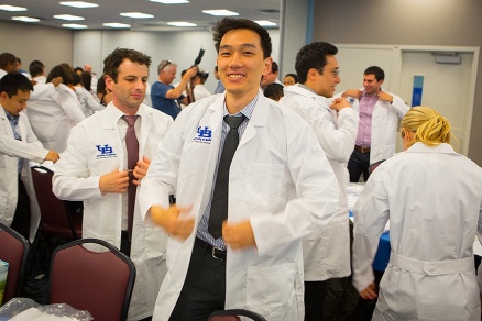 Zoom image: Stephen Chiang, MD, general surgery resident, dons his white coat. Photo: Douglas Levere 