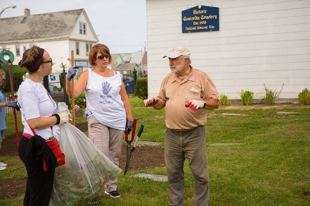 Zoom image: (L-R) Colette Montague, project staff assistant at the School of Pharmacy and Pharmaceutical Sciences, and Ann Marie Cenhard of the IRS speak with Joe Chaya, a director of Concordia Cemetery Association, about maintaining the grounds and markers at the cemetery. Photo: Douglas Levere 