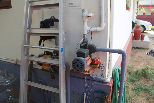 Zoom image: Pumps mounted on the side of homes move water from underground wells to holding tanks on the roof for gravity-fed water usage within the home. 