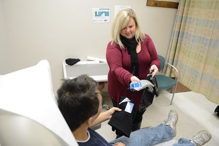Zoom image: Sheila Kennedy hands out gloves to an unnamed patient. Photo: Nancy J. Parisi 