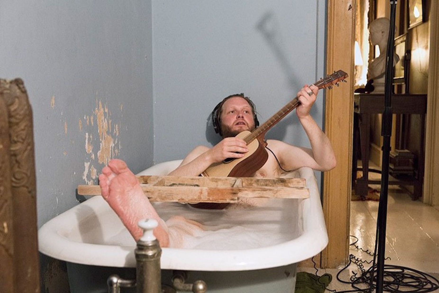 Ragnar Kjartansson in bathtub with guitar. 