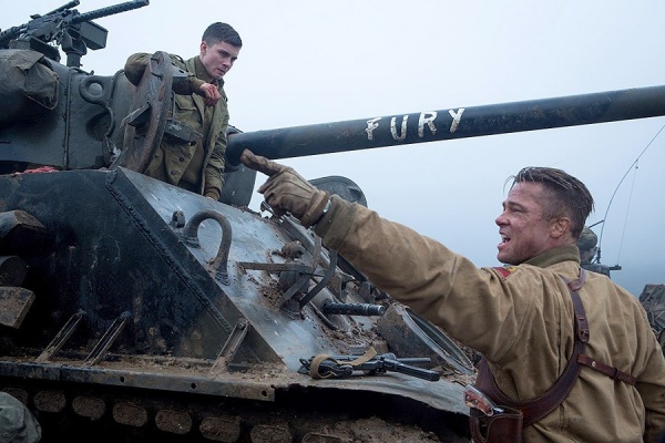 Scene from Fury in which Brad Pitt's character points off to the left while standing in front of a tank with the word "fury" written on the barrel. 