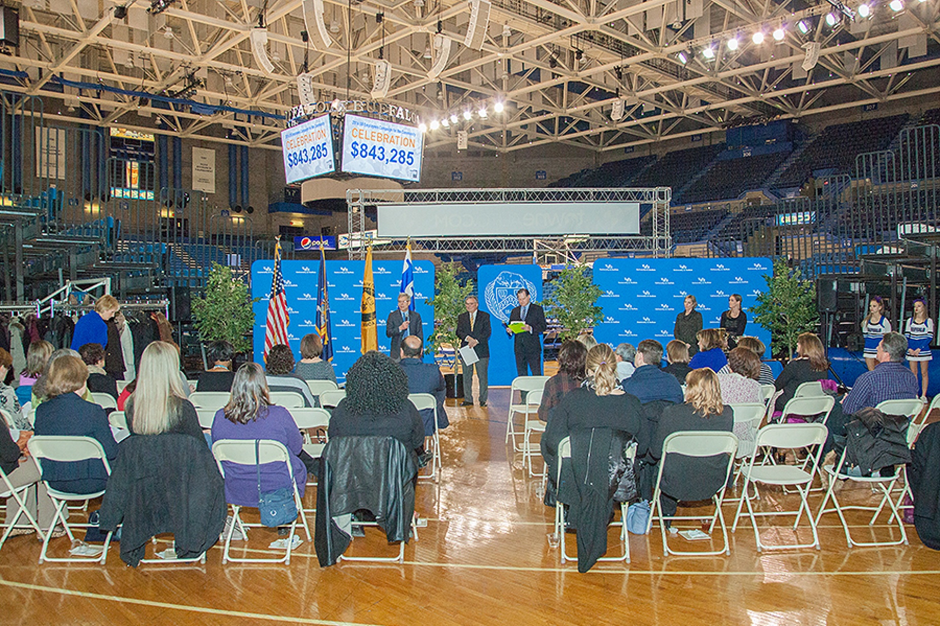 Crowd shot of campaign celebration in Alumni Arena. Jumbotron features total raised; at the front of the room are Provost Charles Zukoski, campaing chair Robert Genco and emcee Paul Peck. 