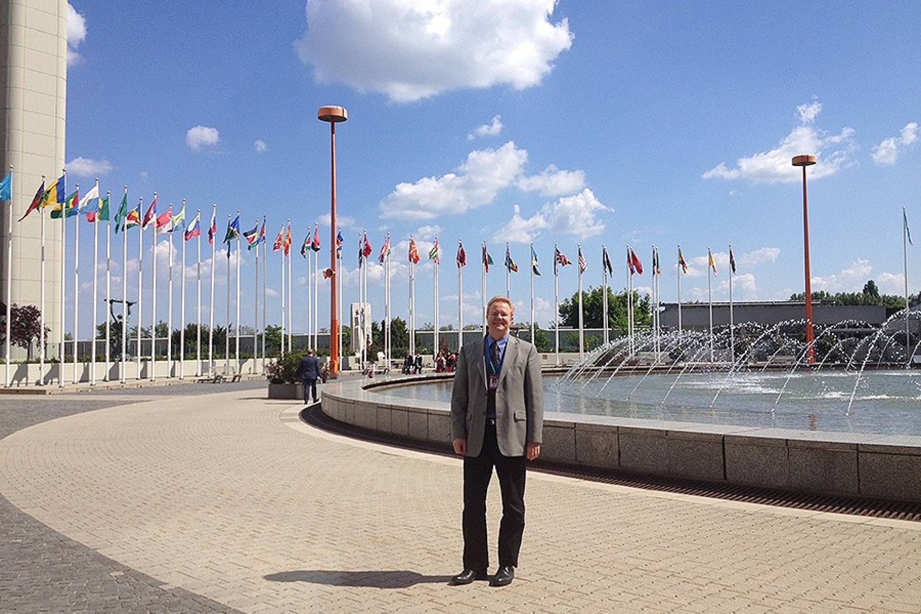 Chris Renschler, surrounded by flags, outside the U.N.'s office at the Vienna International Center in Vienna, Austria. 