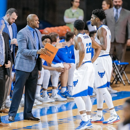 Zoom image: Lindsey Hunter talks with Bulls players Dontay Caruthers (22) and Blake Hamilton. Photo: Paul Hokanson/UB Bulls 
