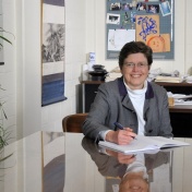 photo of Jo Freudenheim sitting at a table in her office. 