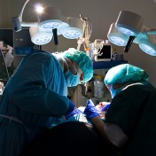 Surgeons in the operating room gathered over a patient. 