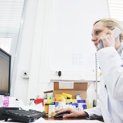 Pharmacist pictured speaking on the phone while looking at a computer monitor. 