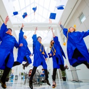 Graduates jump and throw their caps in the air in the CFA atrium. 