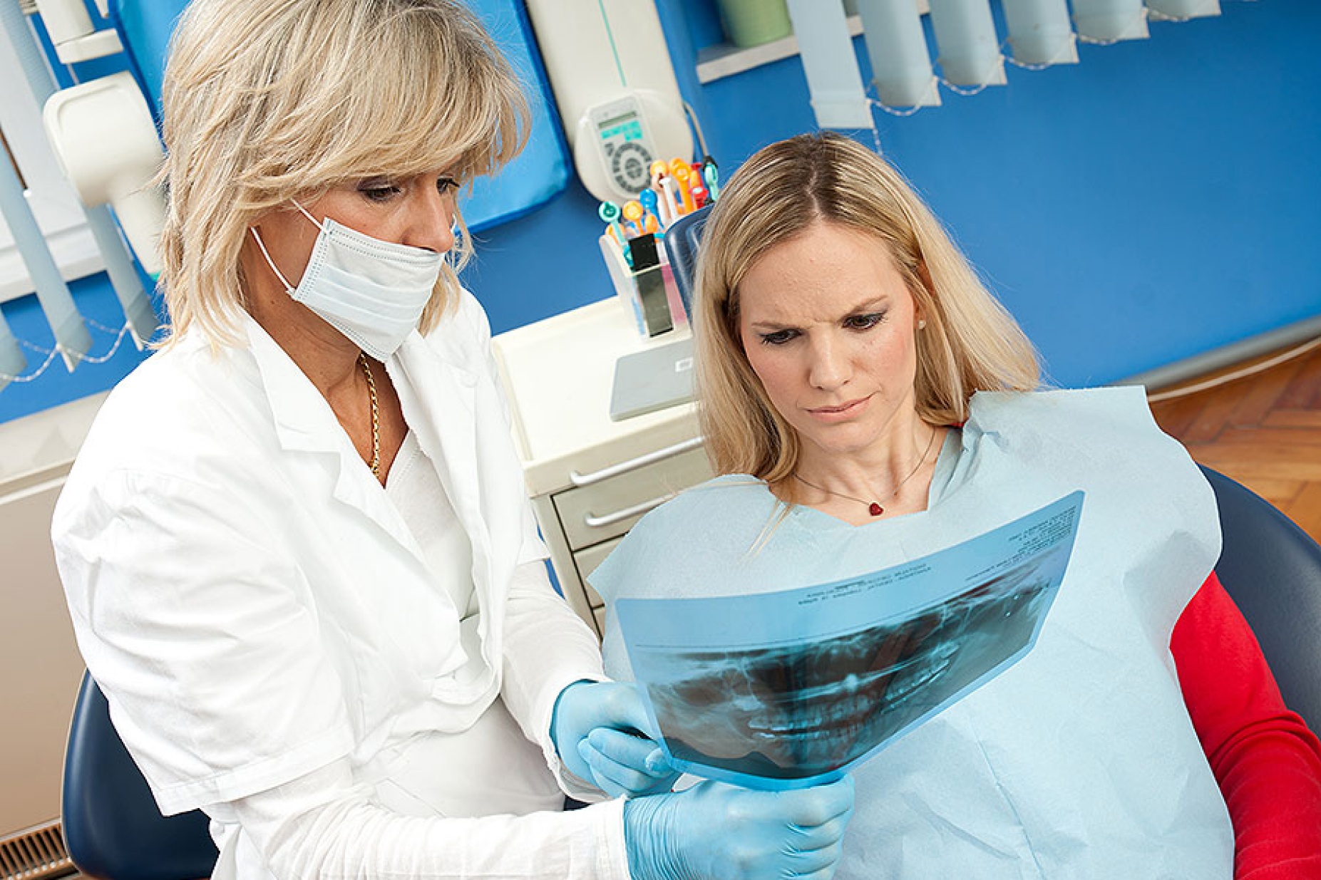 Female dentist reviewing dental x-rays with concerned-looking female patient. 