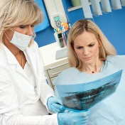 Female dentist reviewing dental x-rays with concerned-looking female patient. 