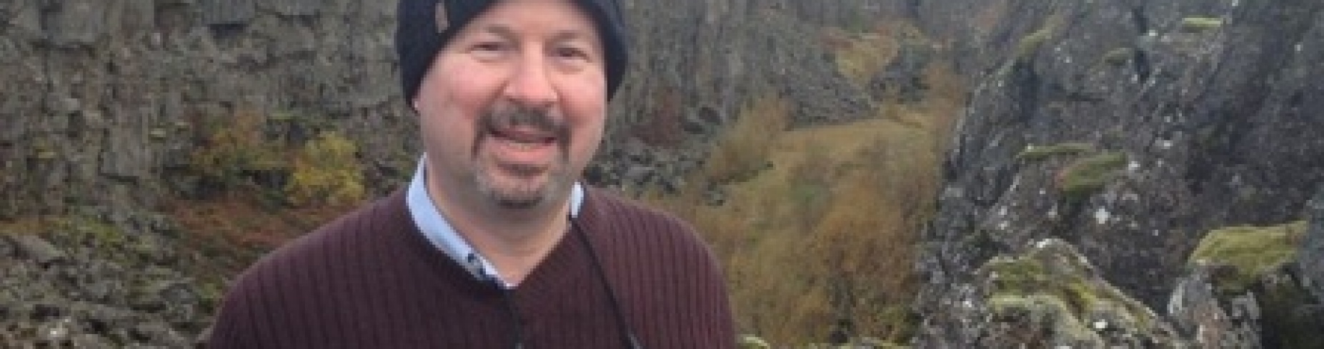 Michael Mann standing in front of a rocky cliff. 