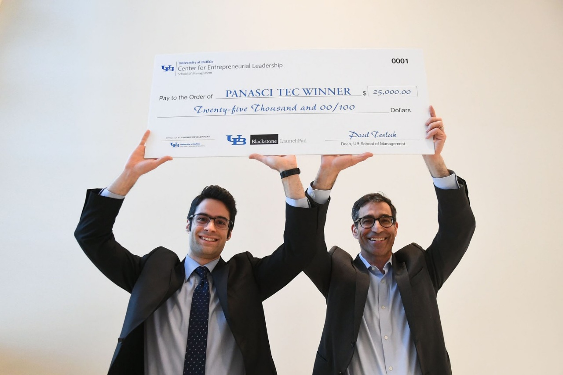 Panasci winners Parham Rohani and S. Bruce Kohrn holding up a big check that reflects their winnings for taking first place. 