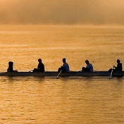 Detail of the "The Boys in the Boat" bookcover photograph of a crew team rowing at sunset. 