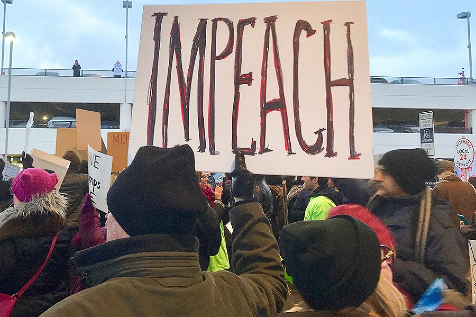 Protester holds up a sign that says "Impeach" at an emergency protest against Muslim ban at Detroit Metropolitan Wayne County Airport's McNamara Terminal on 29 January 2017. 