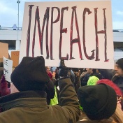 Protester holds up a sign that says "Impeach" at an emergency protest against Muslim ban at Detroit Metropolitan Wayne County Airport's McNamara Terminal on 29 January 2017. 