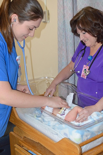 Zoom image: Nicole Raimondi (left), a junior nursing student, and Sisters Hospital nurse Cathleen Incorvia check a baby's heart rate at the mother-and-baby unit at Sisters. Photo: Carrie Sette-Camara 