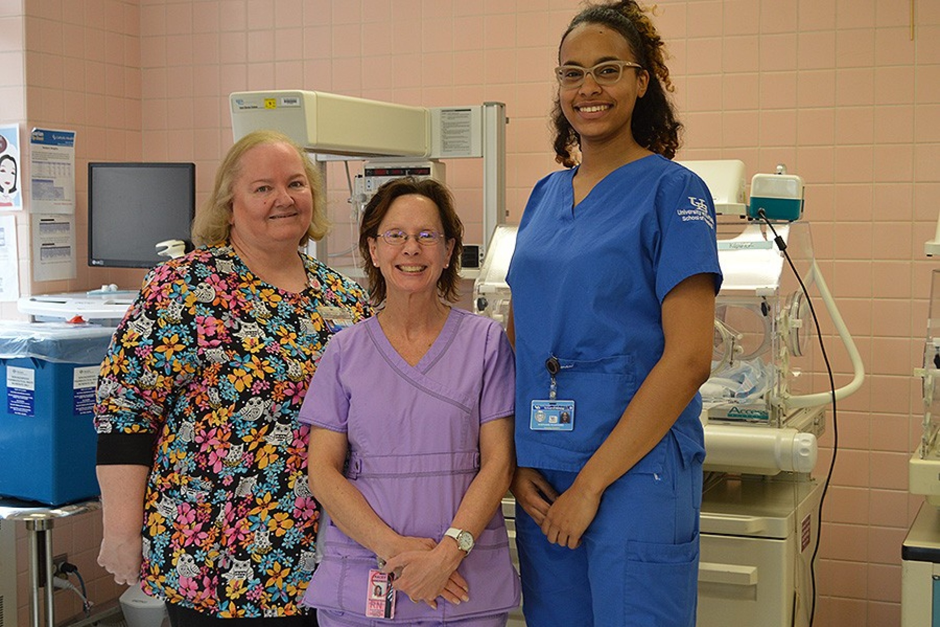 Nursing prof Deborah Raines, Sisters nurse Tracey Zimmerman and student Stephanie Rodriguez in front of an incubator in the mother and baby unit at Sisters. 