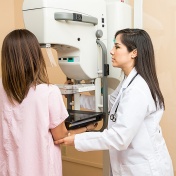 A doctor assists a patient during a mammogram. 