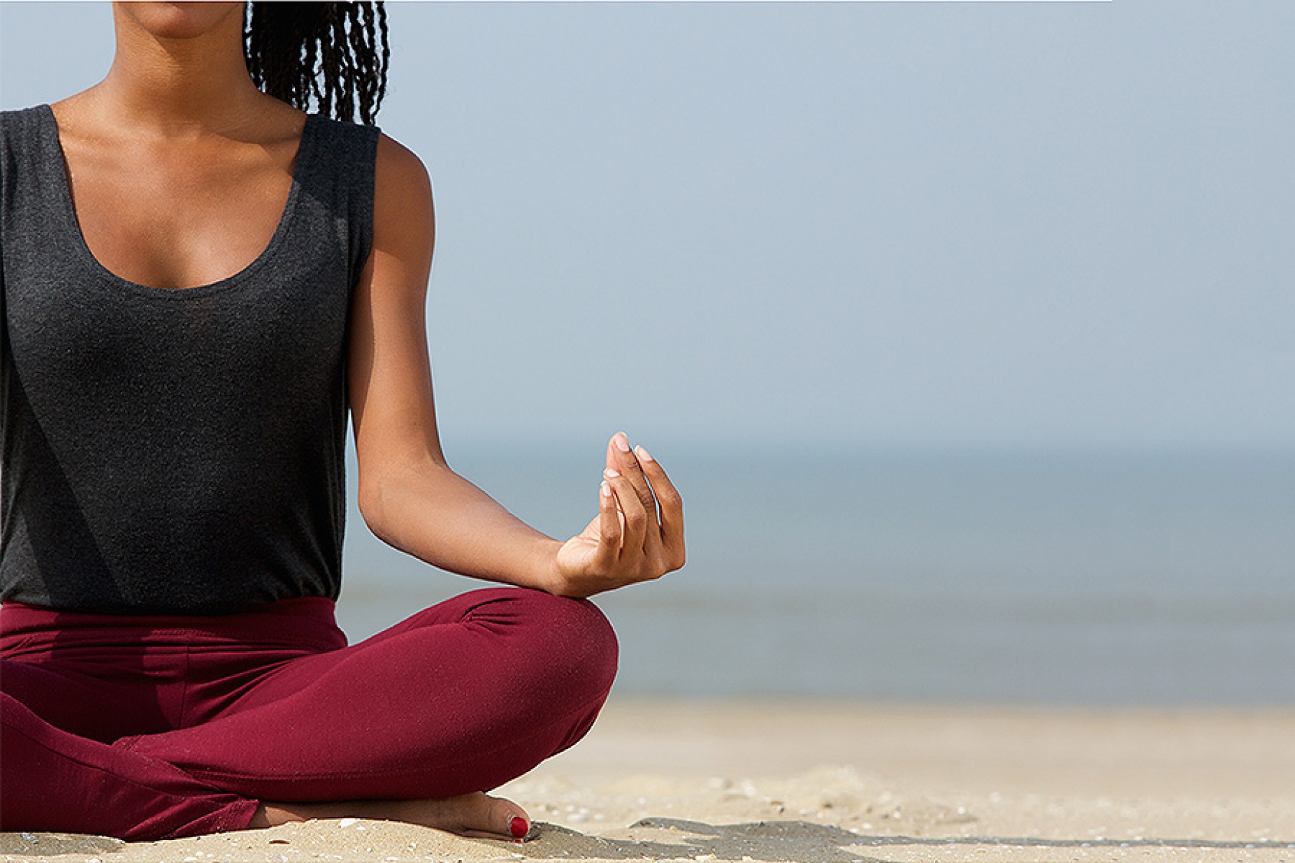 African woman practicing yoga on a beach. 