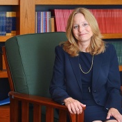 Nellie drew sitting in front of bookshelves. 