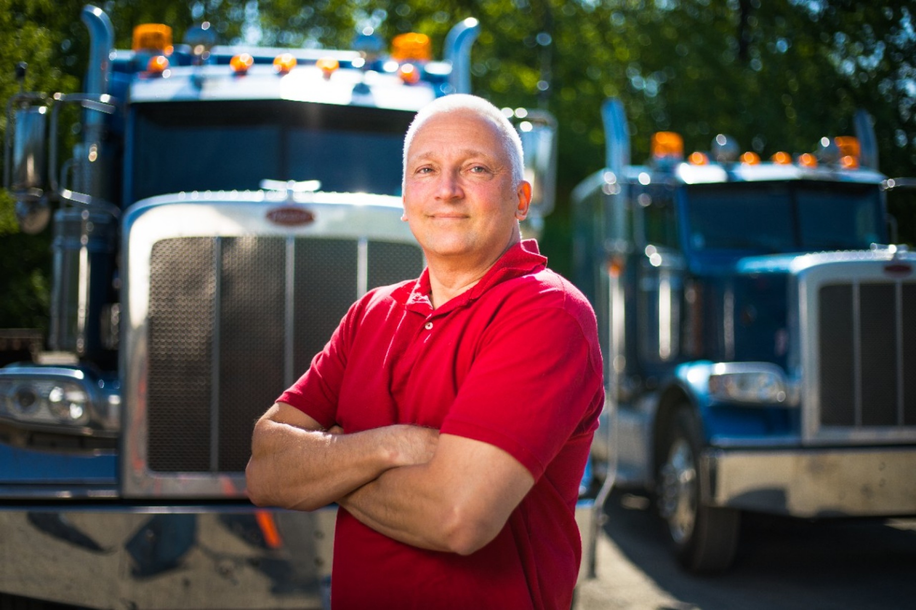 Daniel P. Fuglewicz, director of embedded systems at KeepTruckin, standing in front of two tractor trailers. 