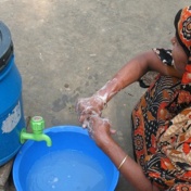 Woman washing her hands at an outdoor hand-washing station. 