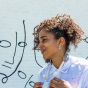 Shantell Martin standing in front of a part of her mural. 