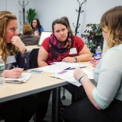 UB students sit around a table with a staffer from the WNY Women&rsquo;s Foundation to discuss their project during the Social Impact Fellows orientation. 