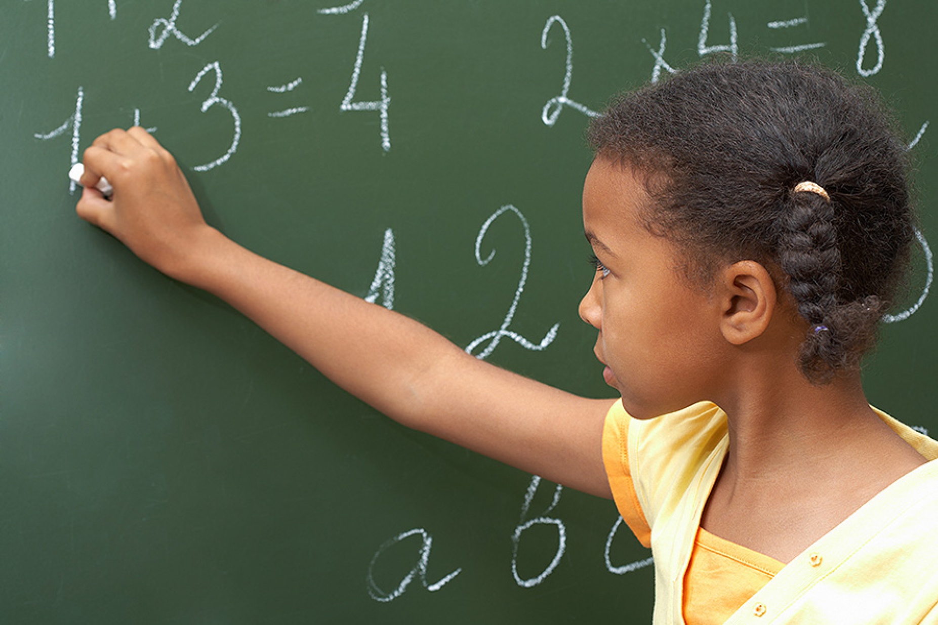 young girl writing math equations at the blackboard. 