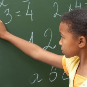 young girl at blackboard writing math equations. 