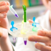 Researcher working in a lab, holding a small vile. 