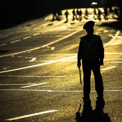 Silhouette of a police officer standing in a street at dusk. 