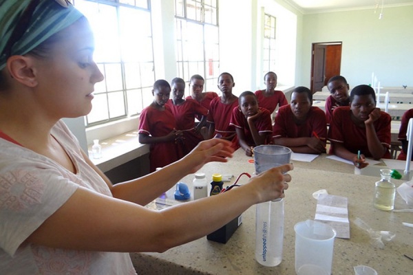 A GEC volunteer does an experiment with Kitenga students to clean dirty water.