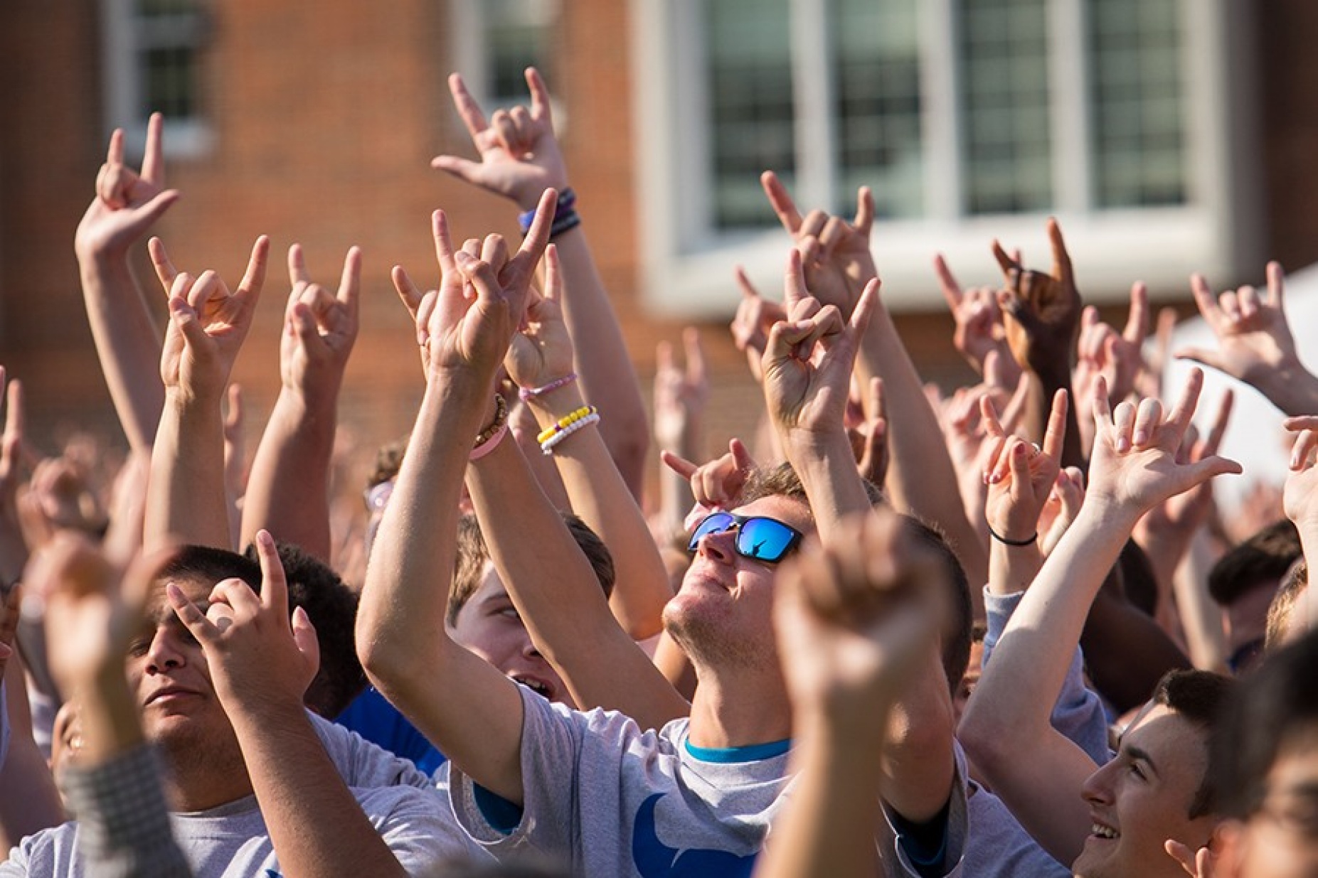 Students gathered in a large group making the "horns up" hand sign. 