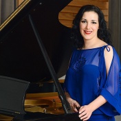 Tiffany Du Mouchelle stands in front of a grand piano. 