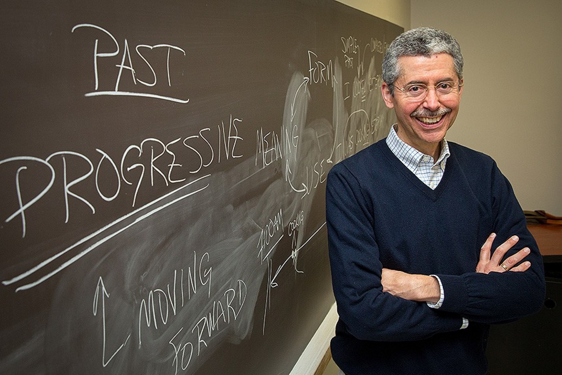 Timothy Cauller stands in front of a chalk board in his classroom. 