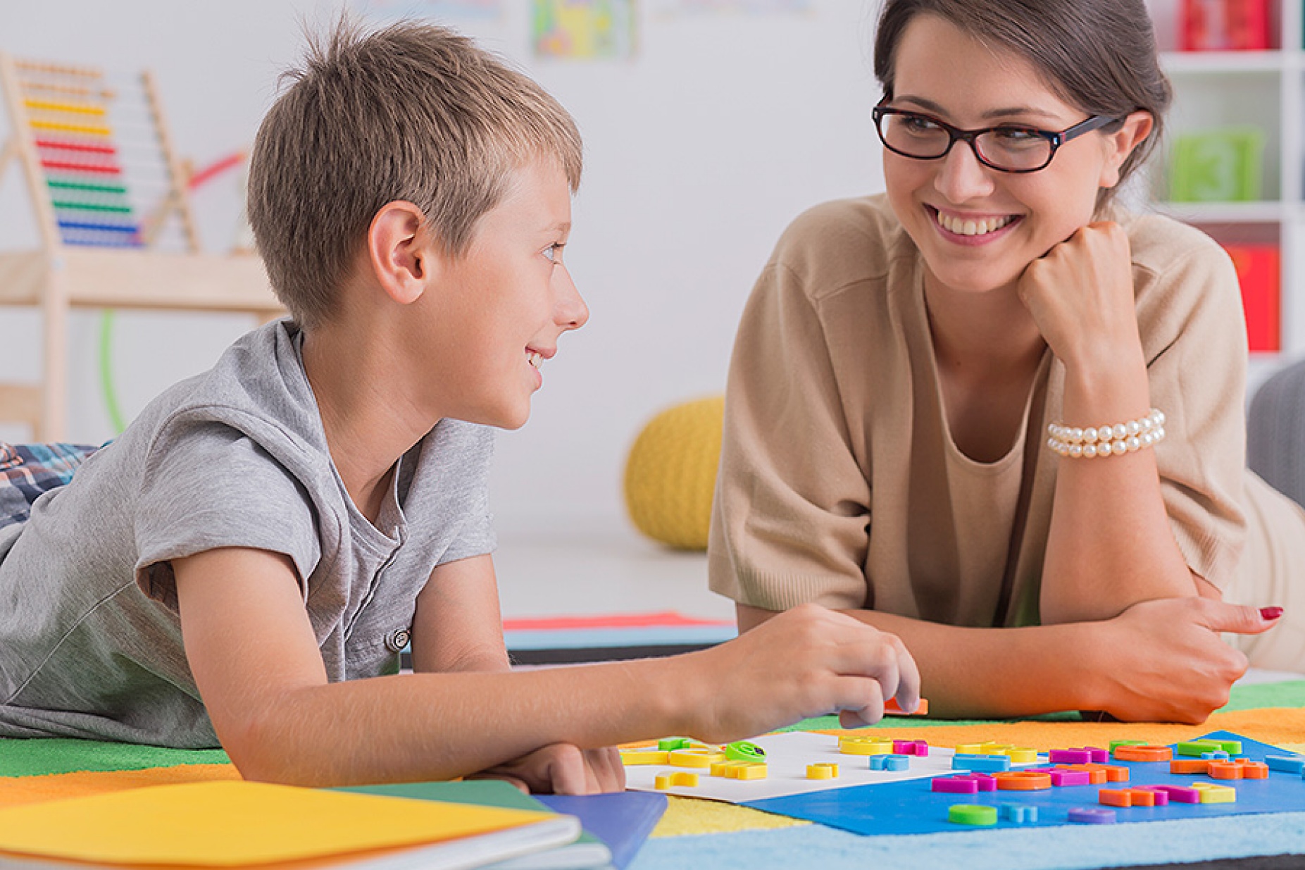 A happy student works with an encouraging teacher. 