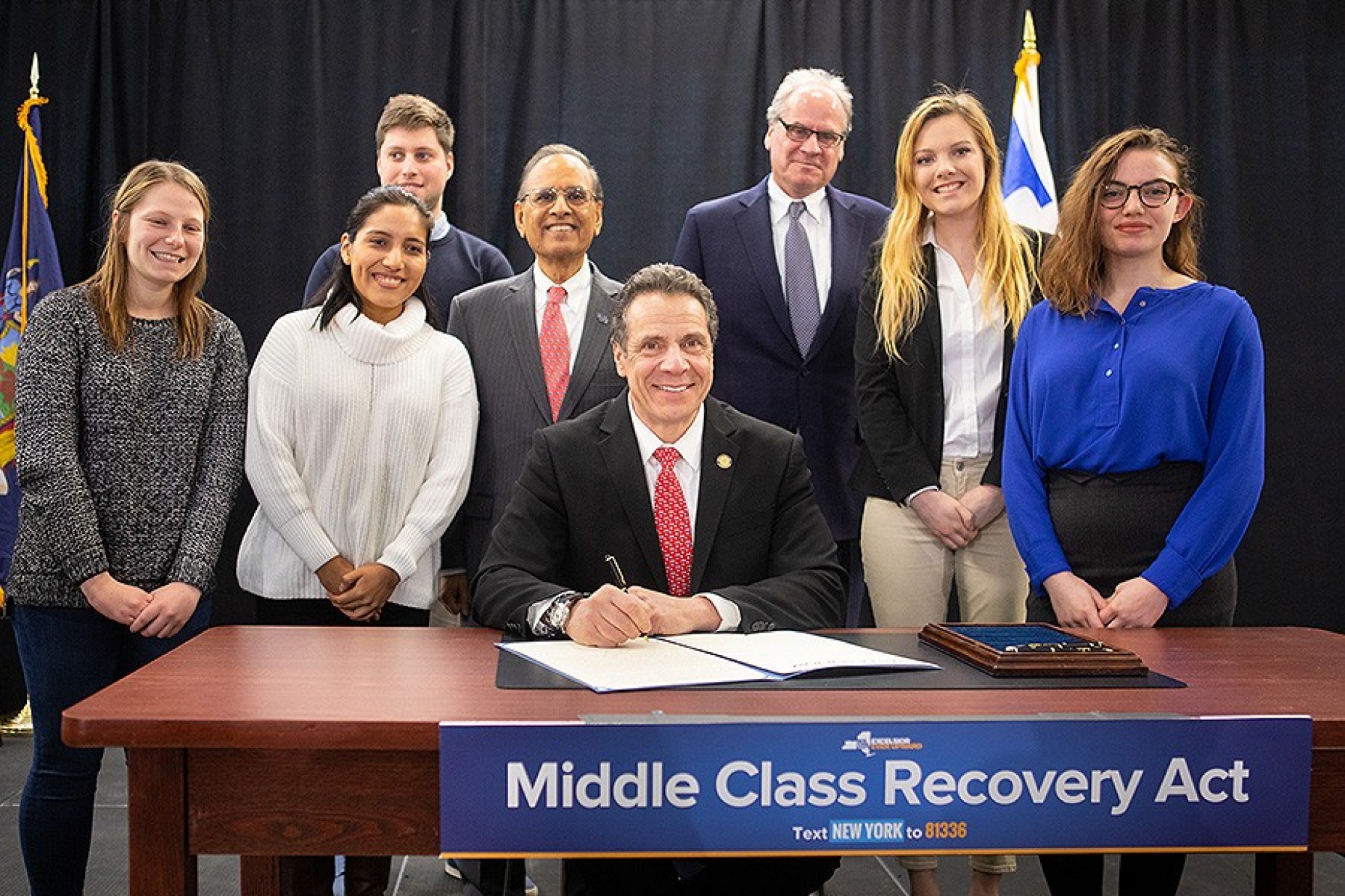 Gov. Andrew Cuomo signing legislation launching second phase of Excelsior Scholarship program surrounded by UB students.