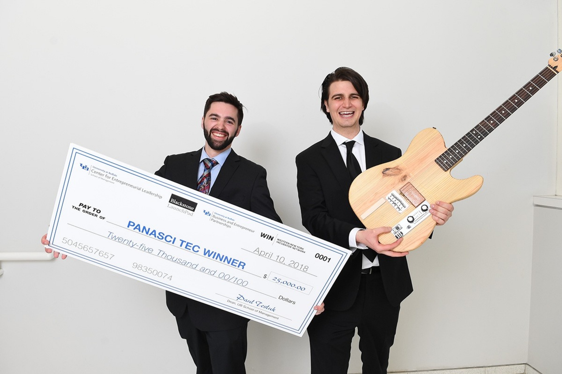 Panasci winners Ryan Jaquin and Shane Nolan holding a giant check and a guitar. 