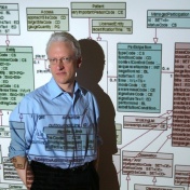 Barry Smith standing in front of a screen projection of data sets. 